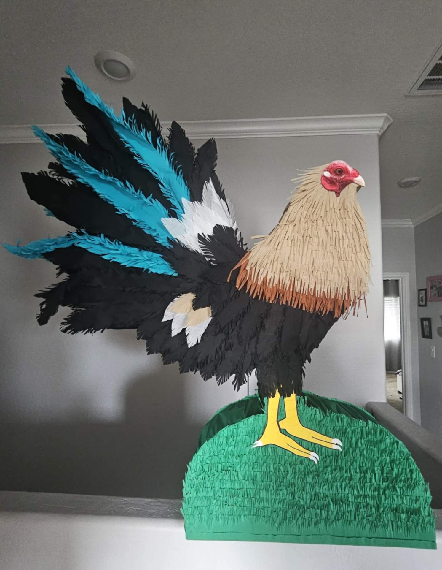 Handmade rooster (gallo) piñata with black, teal, and tan feathers